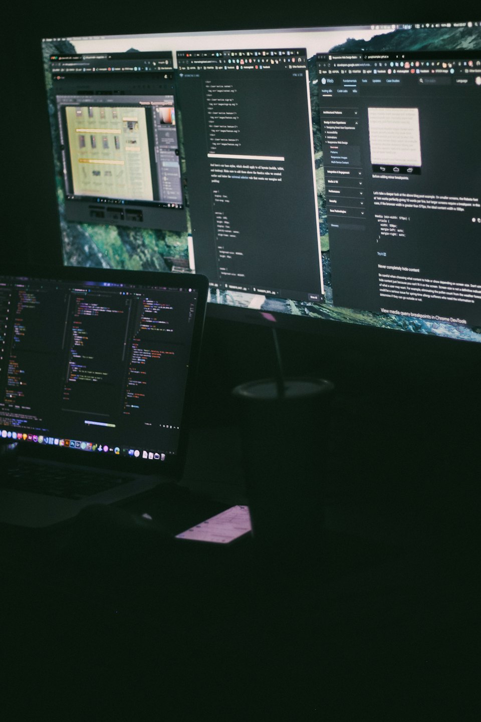 Computer workstation displaying lines of code and design documentation.